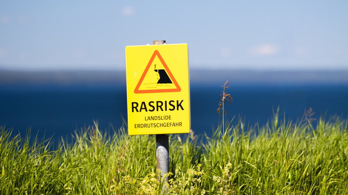 Bright warning sign for landslides in Jönköping, Sweden with scenic ocean view.